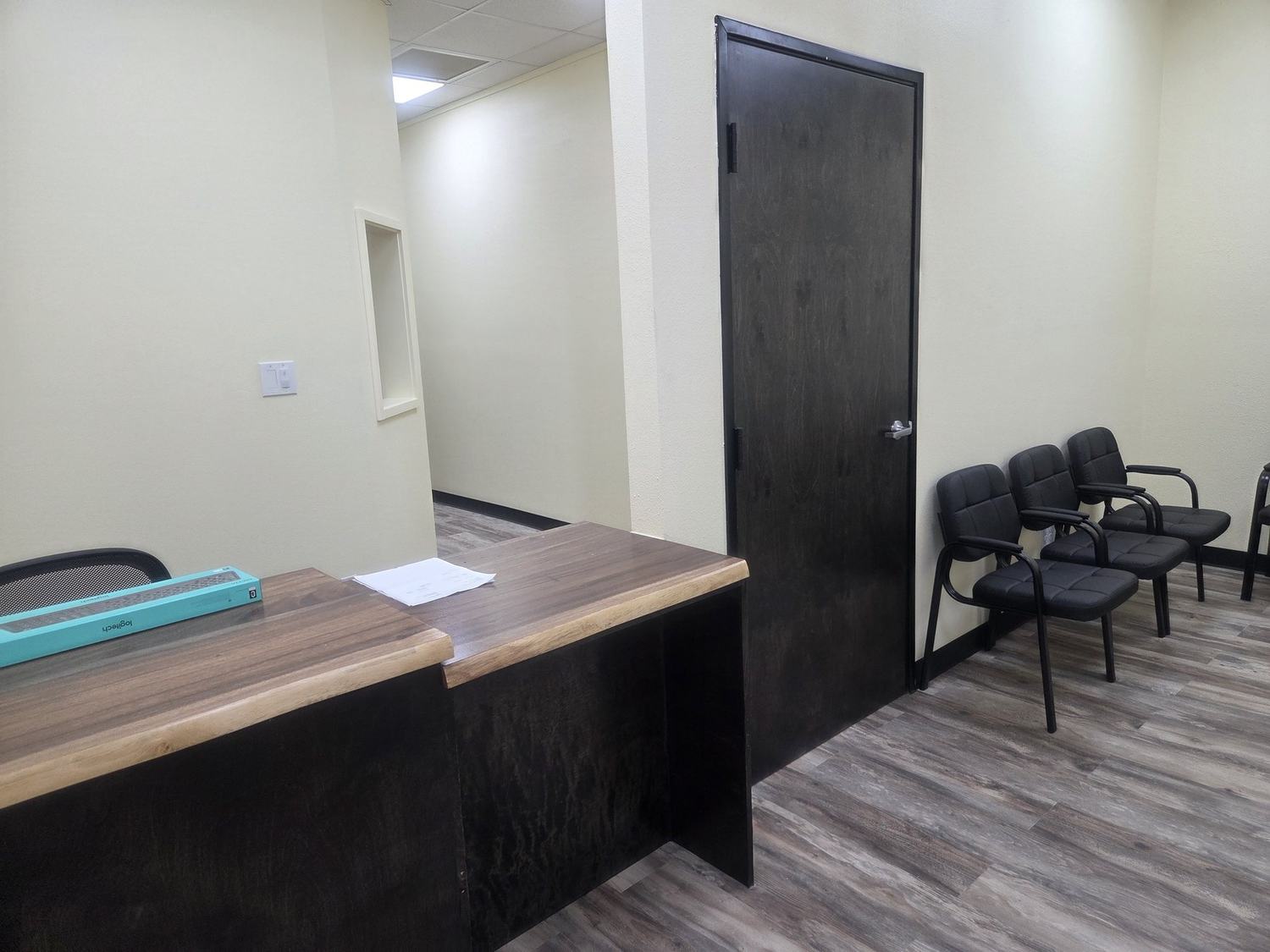 Completed commercial reception area with custom wood desk, flooring, doors, and painted walls