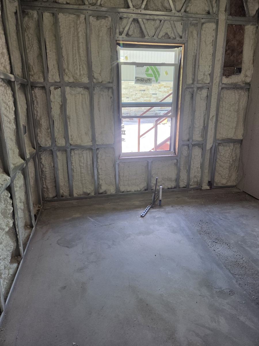 Active construction showing insulated framed walls, window installation, and plumbing rough-in