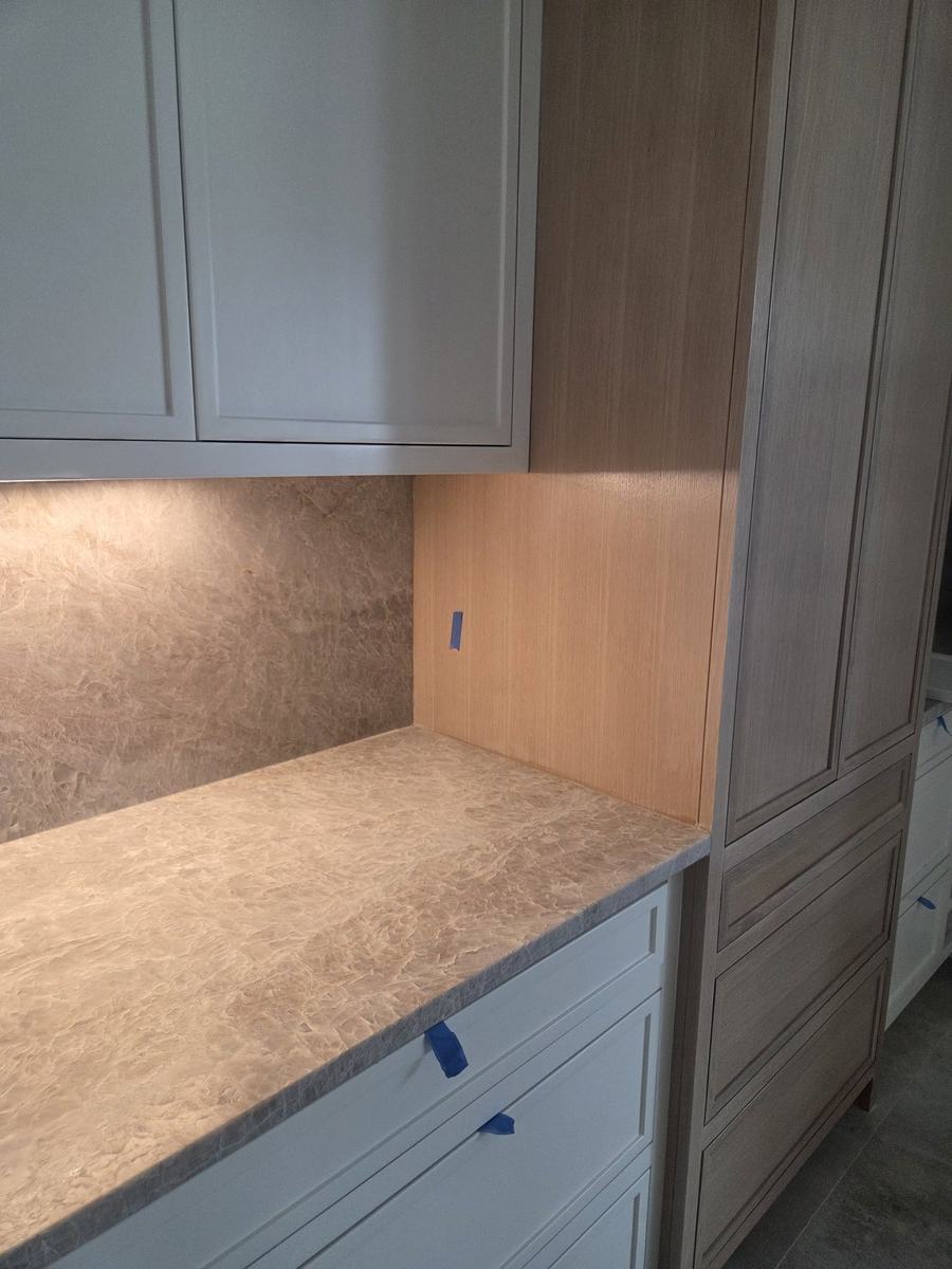 Custom cabinetry with stone countertop, integrated lighting, and wood accent panel
