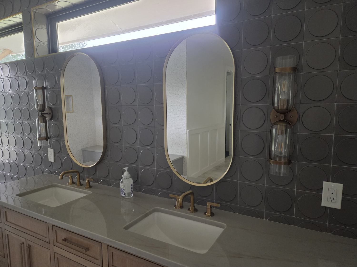 Completed double vanity with decorative tile wall and lighted mirrors