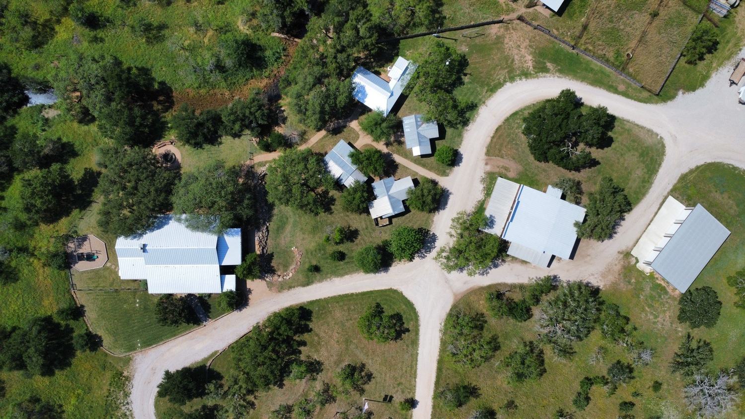 Aerial view of a Hill Country property with multiple completed light-colored metal roofs