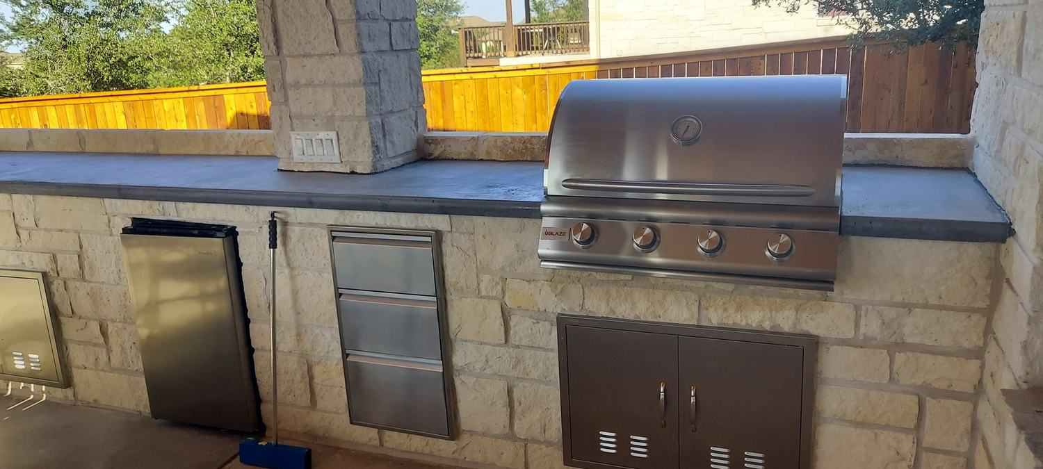Completed stone outdoor kitchen with grill and storage cabinets