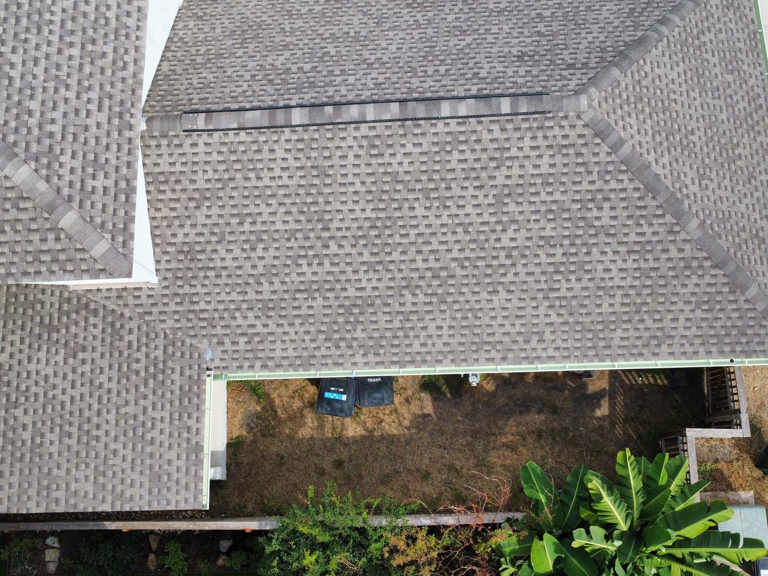 Close aerial view showing finished architectural shingles, ridge caps, and roof valleys